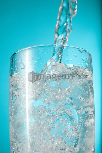 Water pouring into clear glass, nearly full