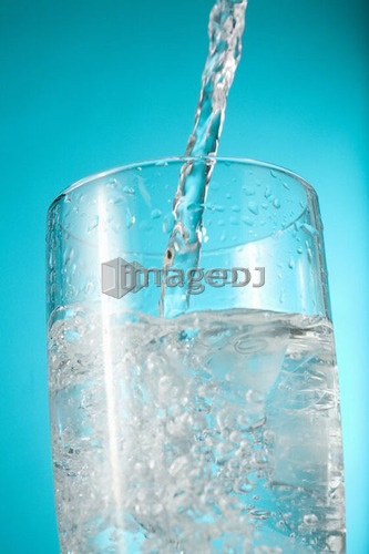 Water pouring into nearly full glass