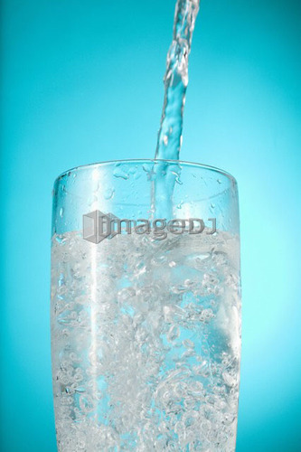 Water pouring into nearly full glass