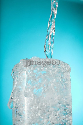 Water pouring into overflowing glass