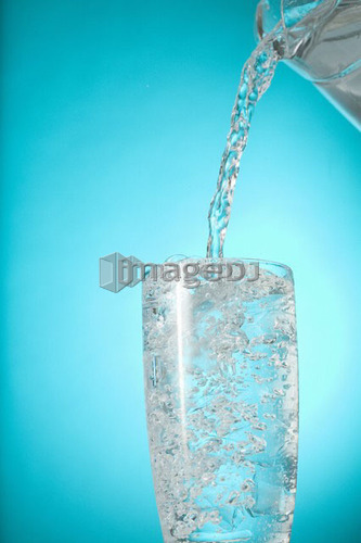 Pitcher of water pouring into very full clear glass