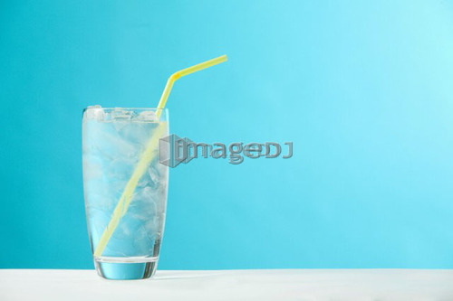 Very full glass of water with ice and yellow drinking straw