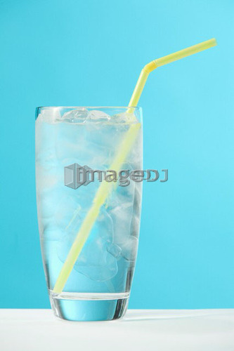 Very full glass of water with ice and yellow drinking straw