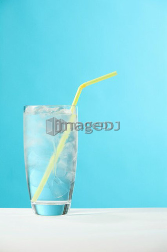 Very full glass of water with ice and yellow drinking straw