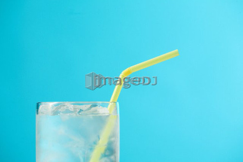 Top portion of very full glass of water with yellow drinking straw