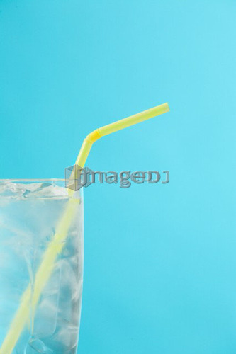Side portion of clear glass of water with yellow drinking straw