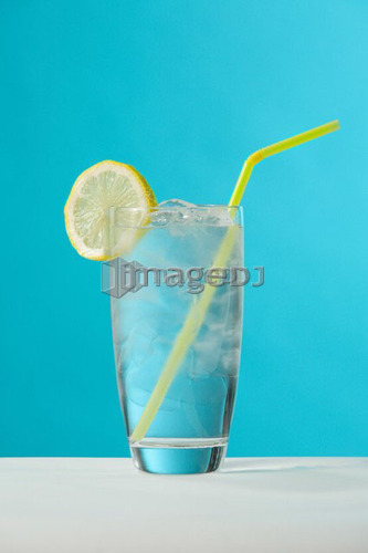 Clear glass of water with lemon and drinking straw