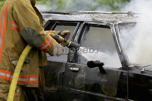 Fire Fighter putting out car fire with hose, Smithville, Ontario