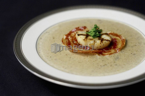 Bowl of Truffled Forest Mushroom Soup with grilled pancetta and scallop garnish