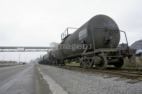Train alongside empty road in industrial setting, Hamilton, Ontario.