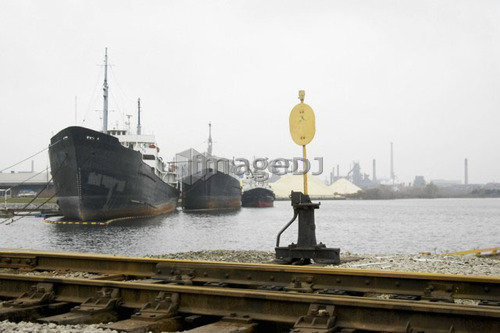Train track, switch stand, and ships against industrial back drop, Hamilton, Ontario.