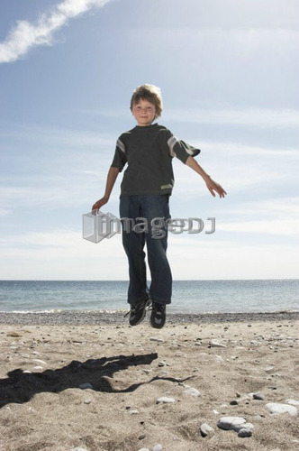 Boy jumping on beach, Whitby, Ontario.