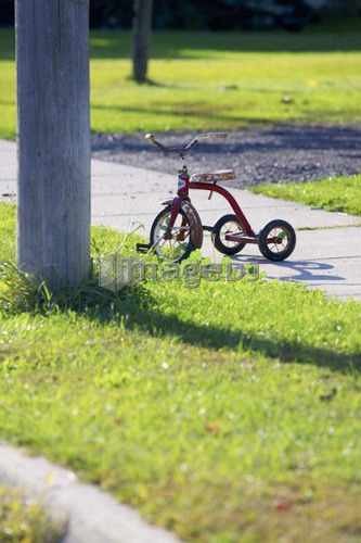 Tricycle on edge of sidewalk beside telephone pole, St. George, Ontario