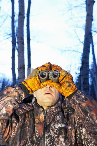 Hunter looking through binoculars, wearing camouflage, Alberta