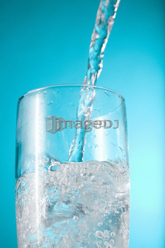 Stream of water being poured into a clear glass
