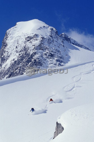 Two young men skiing untracked powder in figure 8's, Bugaboo Glacier Provincial Park, British Columbia, Canada