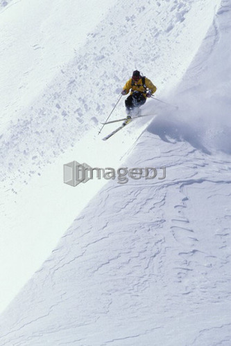 Young man skiing fresh powder on steep slope at Island Lake Resort, Fernie, British Columbia, Canada.