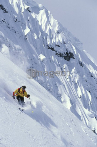 Young man skiing fresh powder on steep slope at Island Lake Resort, Fernie, British Columbia, Canada.