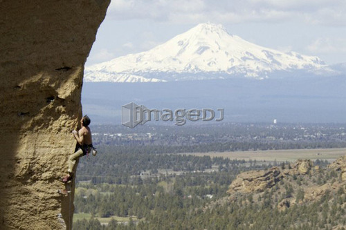 Man (25-30) rock climbing with Mountain in background, Smith Rock State Park, Oregon, USA