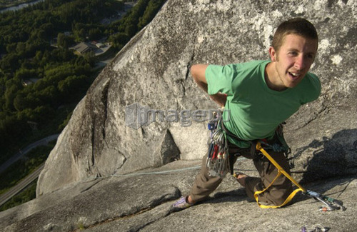 Man (20-25) hanging from rock anchors on a granite rock face, Squamish, B.C.