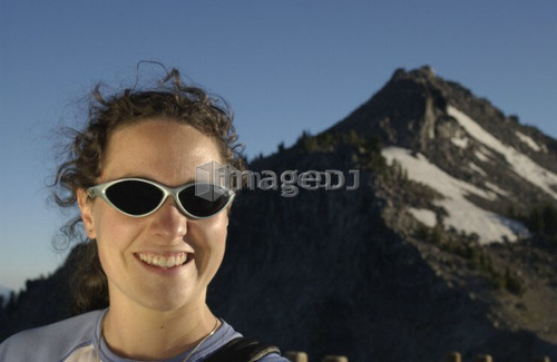 Woman (20-25) with sunglasses in front of mountains, Crater Lake National Park, Oregon