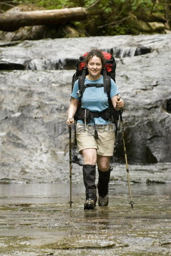 Woman (20-25) hiking along a sandstone creek bed in an old-growth coastal forest, West Coast Trail, Pacific Rim National Park Re