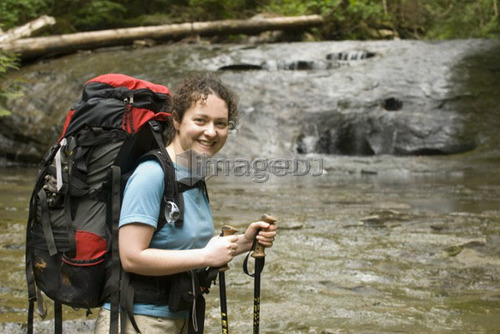 Smiling Woman (20-25) standing beside a sandstone creek bed in an old-growth coastal forest, West Coast Trail, Pacific Rim Natio
