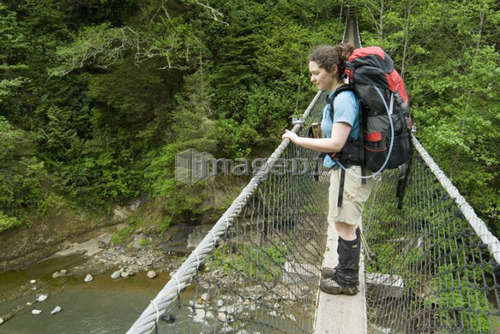 Woman (20-25) looking out from a suspension bridge in an old-growth coastal forest, West Coast Trail, Pacific Rim National Park 