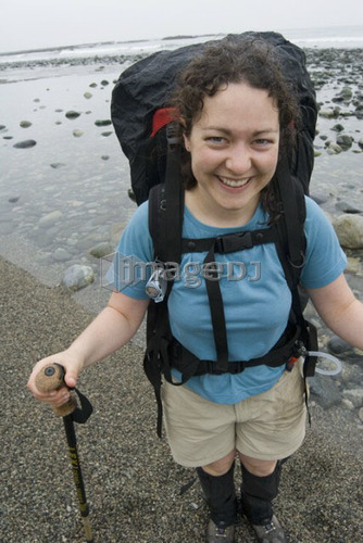 Smiling Woman (20-25) on a beach with a large backpack on, West Coast Trail, Pacific Rim National Park Reserve, BC