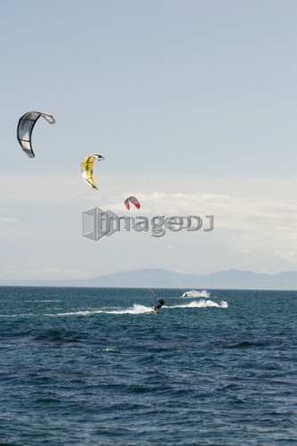 Three kiteboarders on the ocean with colourful kites, Victoria, BC