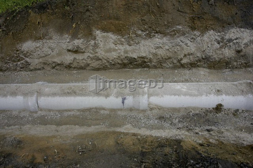 Drainage pipe half buried in earth; Canada, Ontario, Hamilton (Composting Facility)