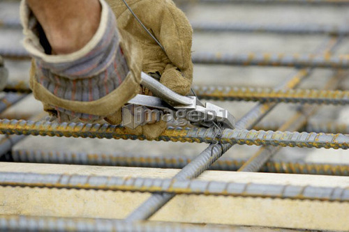 Workers gloved hands tying rebar with pliers and metal wire; Canada, Ontario, Hamilton (Composting Facility)