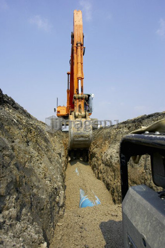 Excavator filling in section of drainage pipe with dirt; Canada, Ontario, Hamilton (Composting Facility)