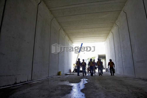 Workers walking down a concrete tunnel; Canada, Ontario, Hamilton (Composting Facility)