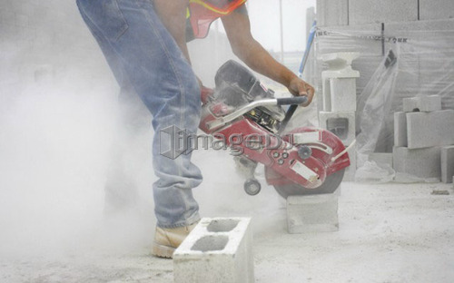 Worker cutting a cinder block with a circular saw; Canada, Ontario, Hamilton (Composting Facility)