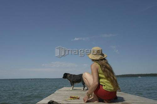 Woman and dog on dock, Clear Lake; Canada, Manitoba, Riding Mountain National Park