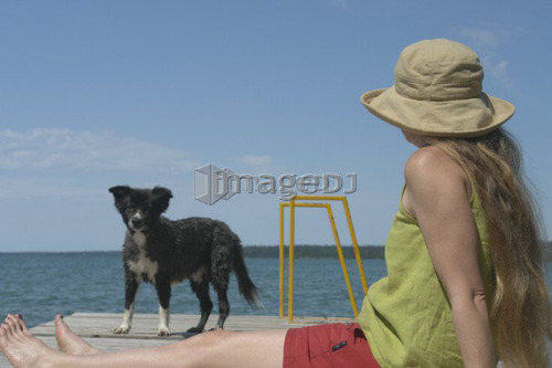 Woman and dog on dock; Canada, Manitoba, Riding Mountain National Park