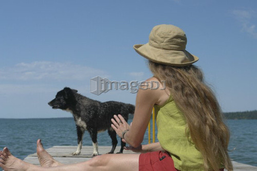 Woman and dog on dock; Canada, Manitoba, Riding Mountain National Park
