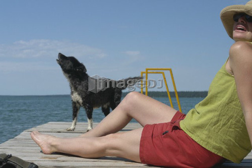 Woman and dog on dock; Canada, Manitoba, Riding Mountain National Park