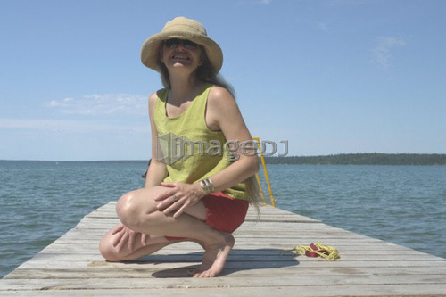 Woman on dock; Canada, Manitoba, Riding Mountain National Park