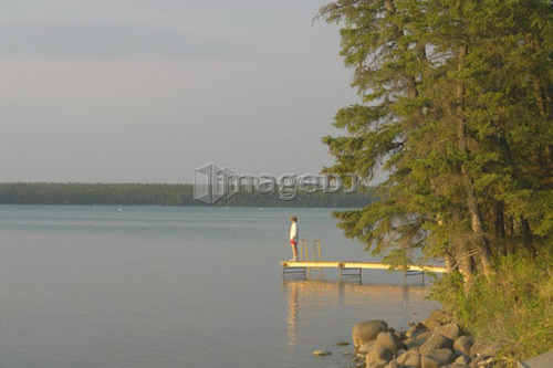 Woman on dock Clear Lake; Canada, Manitoba, Riding Mountain National Park