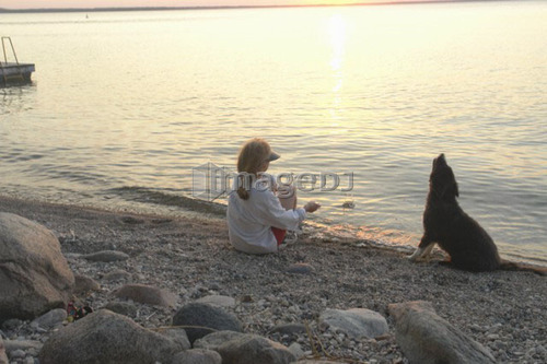 Woman with dog at beach Clear Lake; Canada, Manitoba, Riding Mountain National Park