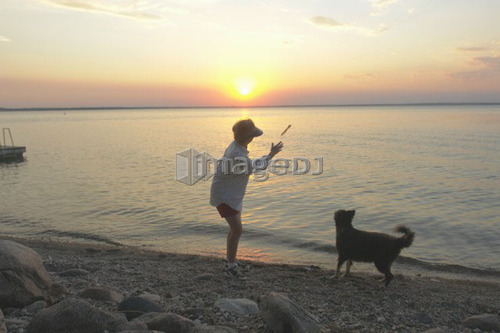 Woman with dog at beach Clear Lake; Canada, Manitoba, Riding Mountain National Park