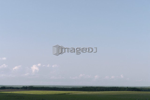 Vista of green fields and distant hills; Canada, Manitoba, Erickson