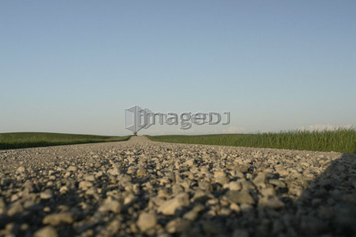 Extreme low angle of gravelled country road with oncoming vehicle; Canada, Manitoba, Erickson