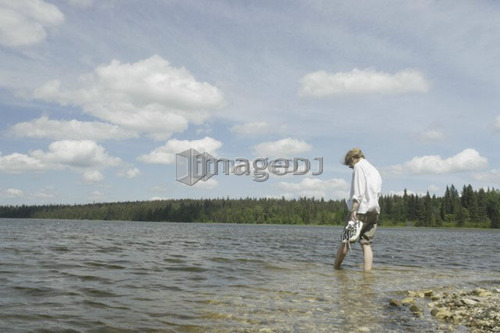 Woman wading in Clear Lake; Canada, Manitoba, Riding Mountain National Park