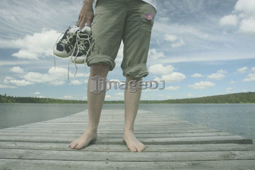 Woman standing on dock, Clear Lake; Canada, Manitoba, Riding Mountain National Park