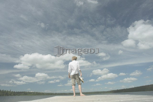 Woman standing on dock, Clear Lake; Canada, Manitoba, Riding Mountain National Park