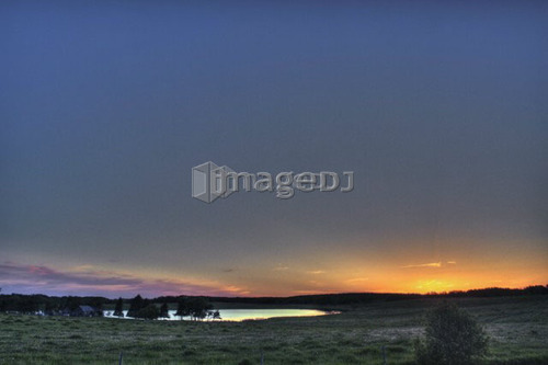 Sunset over farmland and slough; Canada, Manitoba, Erickson