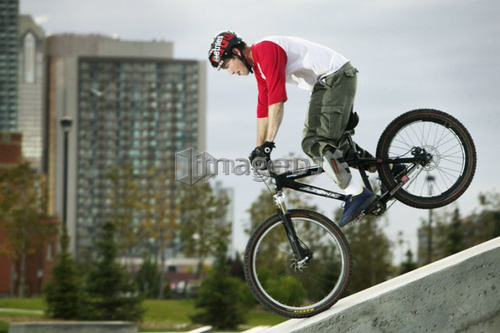 Profile of youth on mountain bike, city tower in background, Alberta, Calgary, Shaw Millenium Park